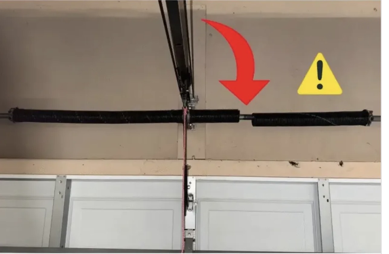Broken garage door torsion spring with a red arrow pointing to the break